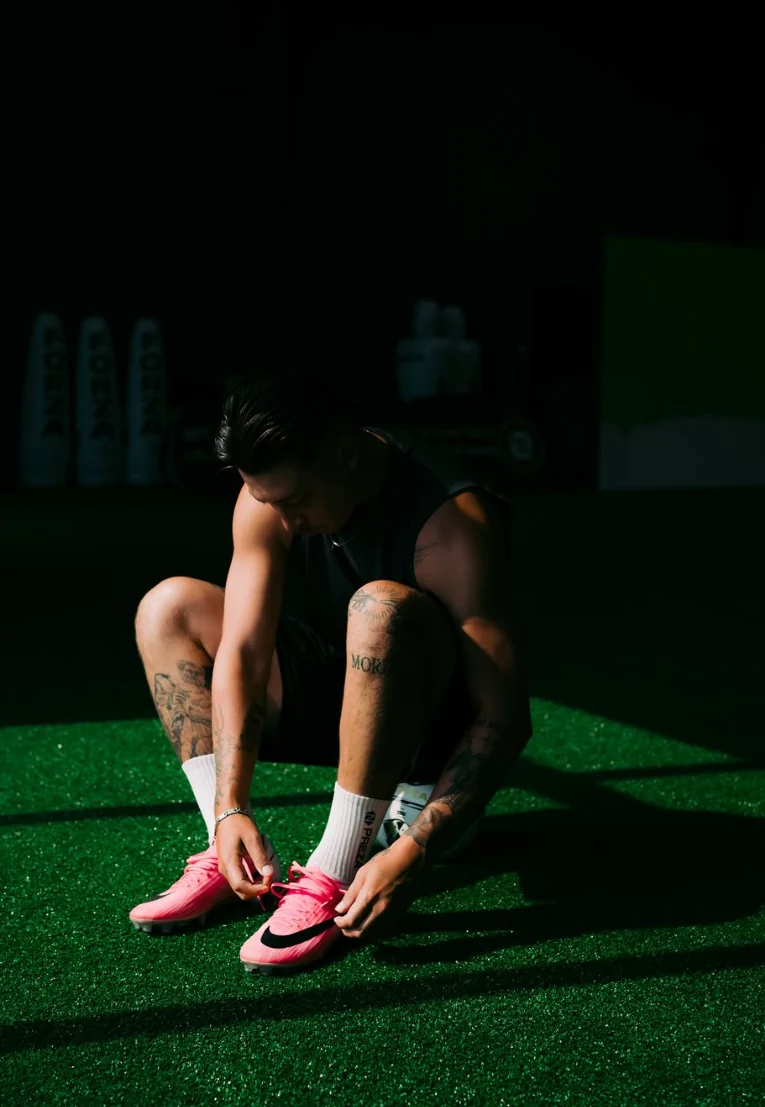 THE90’s owner lacing pink soccer footwear on the indoor turf